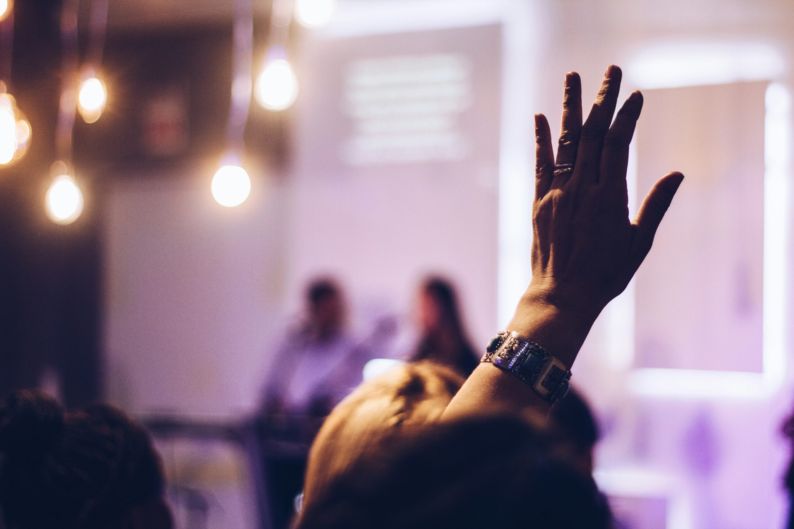 Person raising hand at conference for sustainable event and corporate consulting