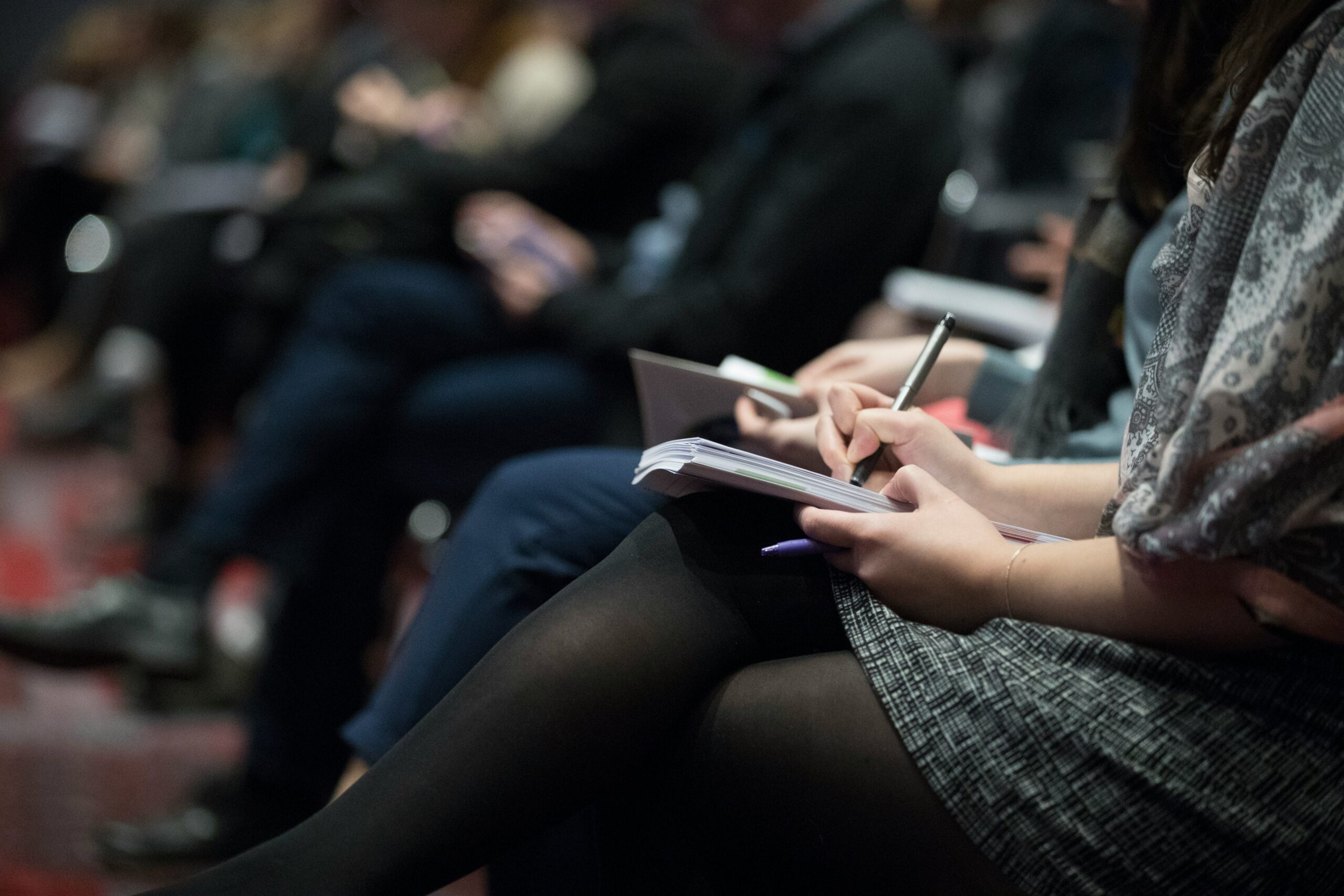 Woman writing in notebook at event for sustainable conference consulting