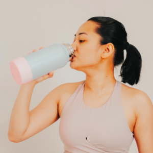 Female drinking from water bottle for low-waste and sustainable corporate and event gifts and swag Food and Drink category